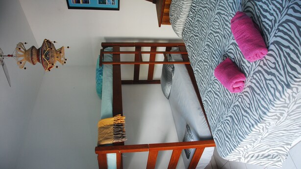 A room with a bed, a wooden headboard, a zebra-patterned blanket, and a blue wall with a framed picture.