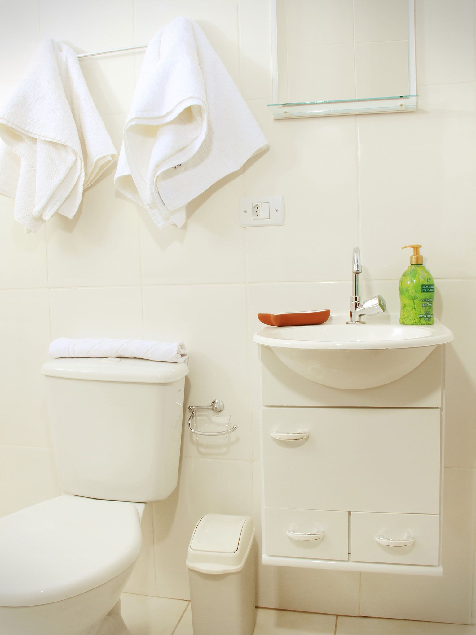 Une salle de bain équipée de toilettes, d’un lavabo et d’une douche à parois en verre.