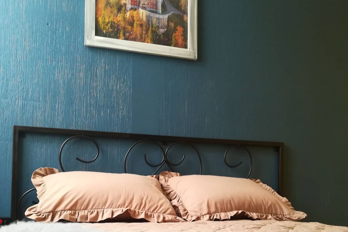 Ein Schlafzimmer mit einem Bett, einem Kopfteil und einem Gemälde an der Wand.