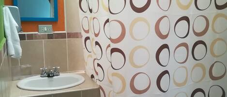 A bathroom with a sink, mirror, and shower curtain.