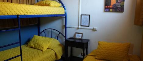 A dormitory room with bunk beds and a desk.