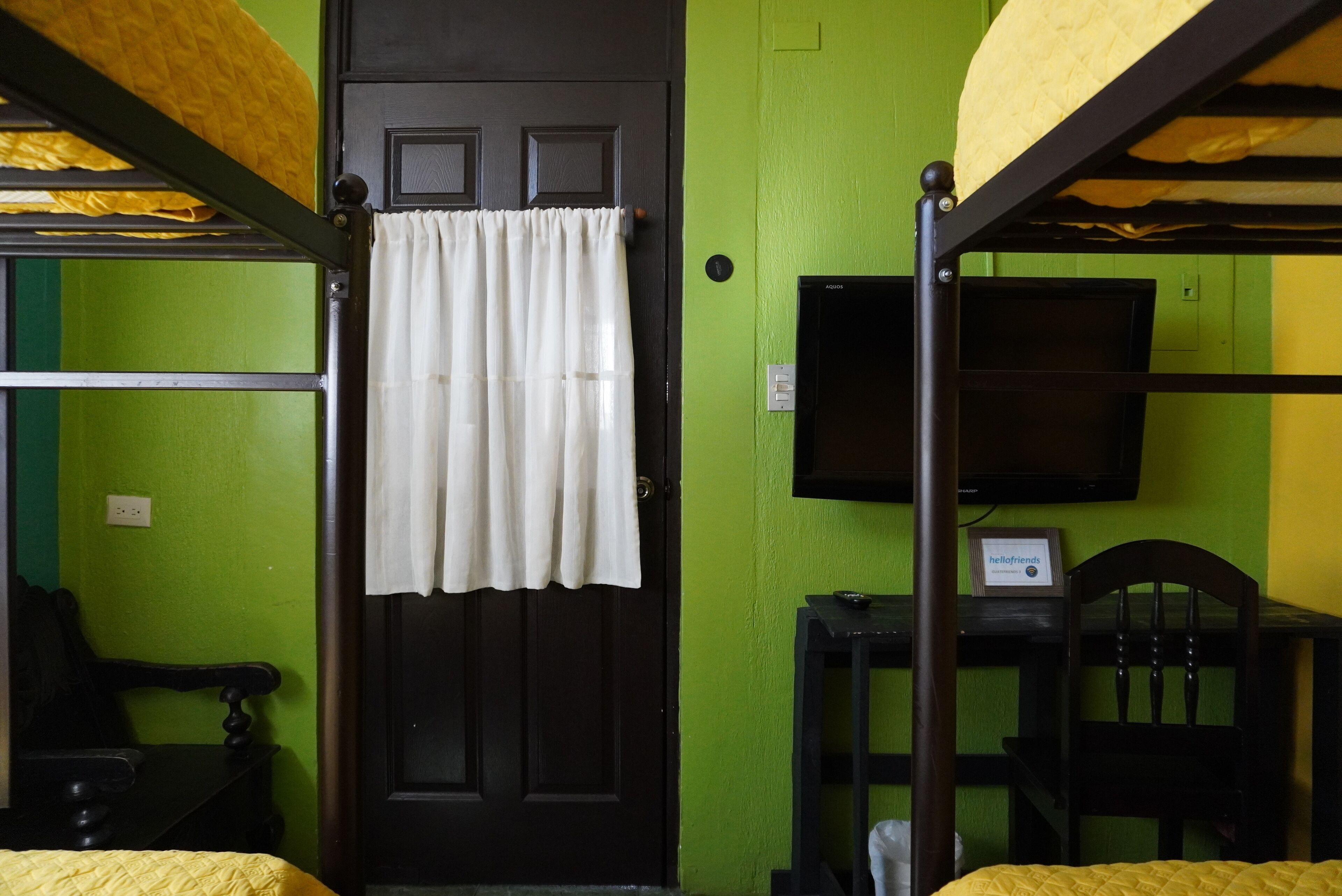 A bunk bed room with a door, a television, and a chair.