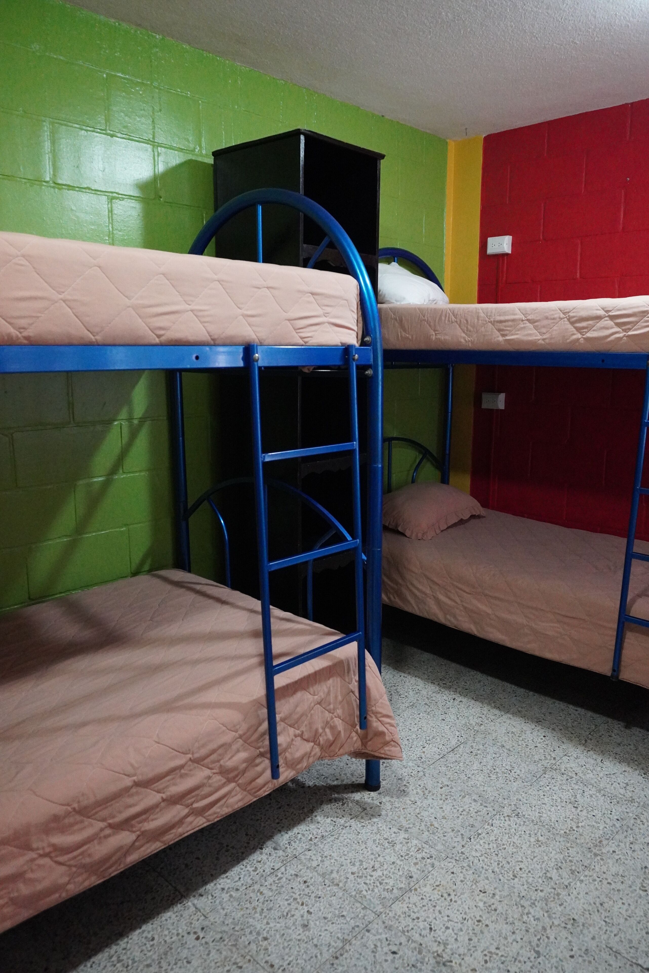 Camas literas en una habitación con paredes verdes y rojas.
