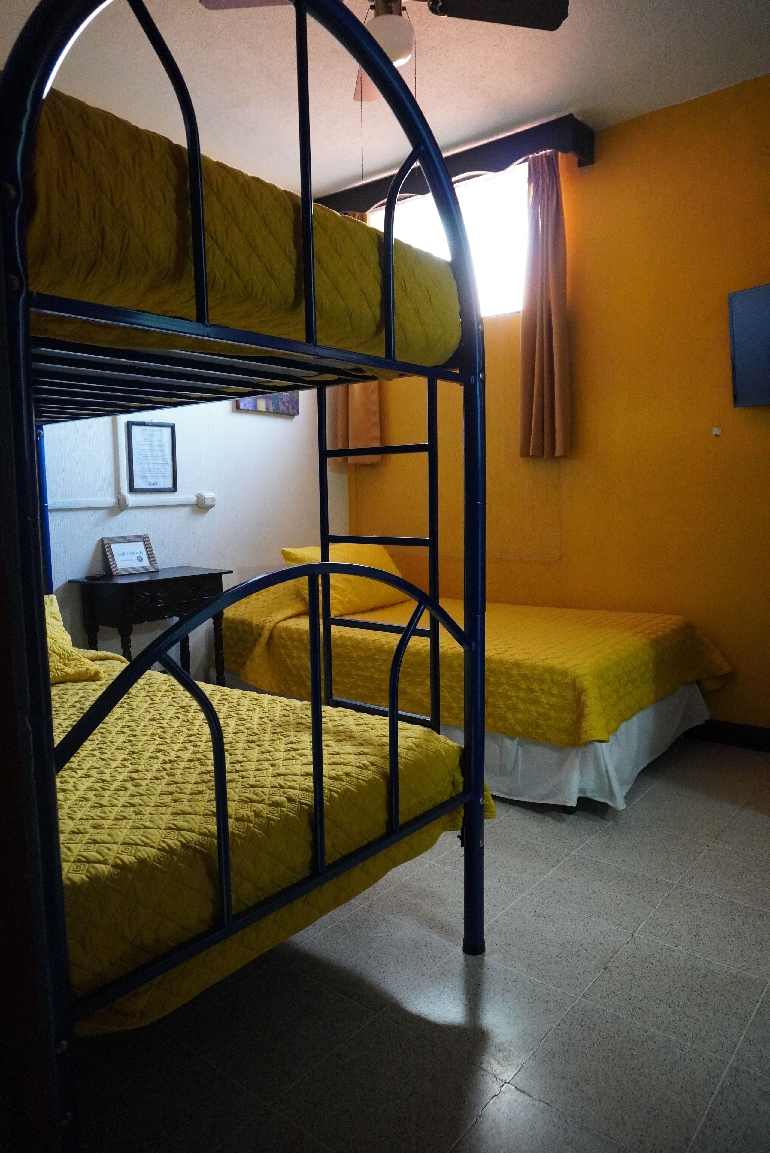 A dormitory room with bunk beds, a small table, and a wall-mounted TV.
