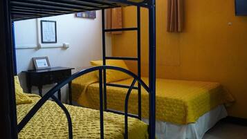 Un dormitorio con literas, una mesita pequeña y un televisor de pared.