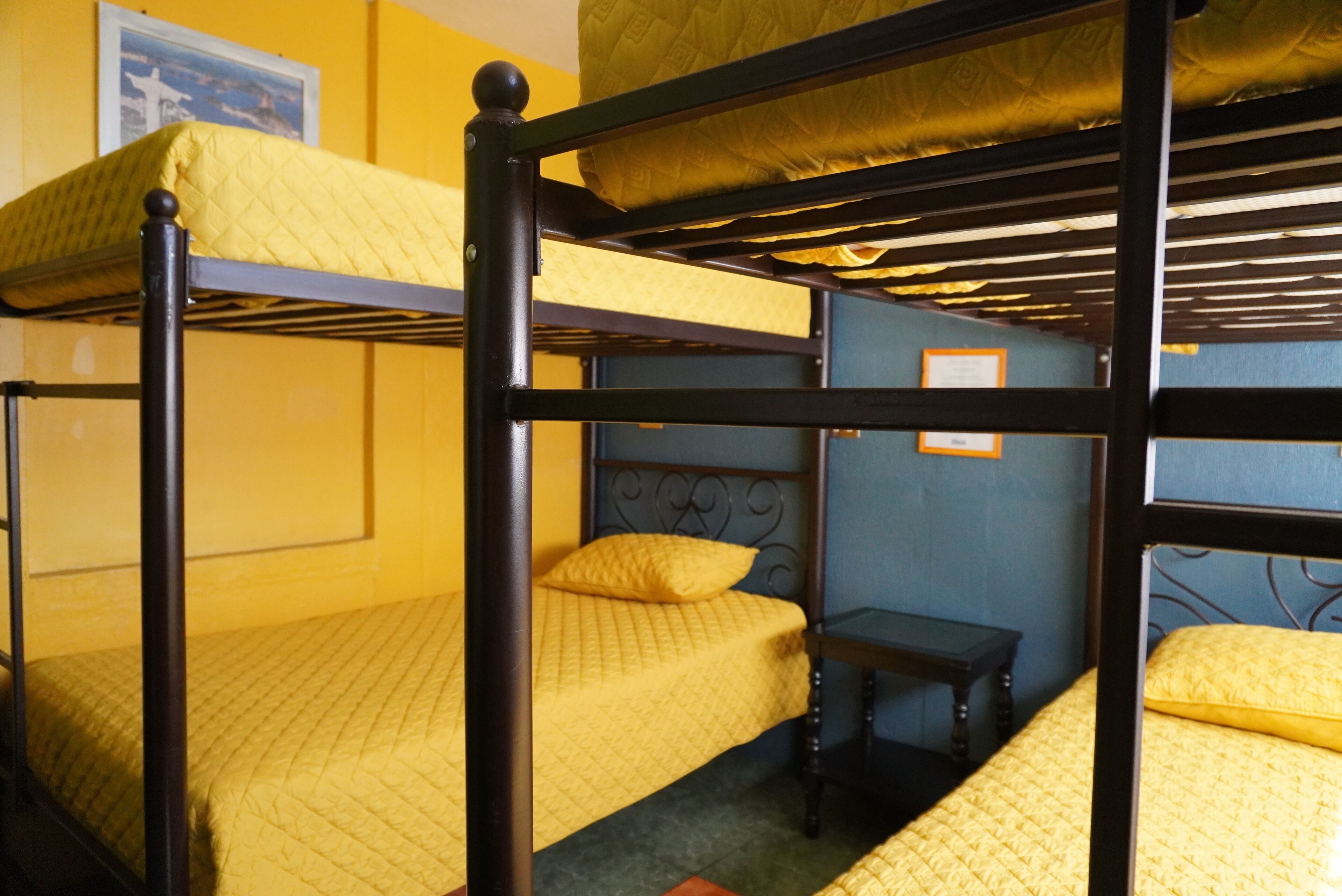 Habitación con literas, ropa de cama amarilla y cabecera de madera.