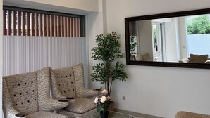 A modern living room with two patterned armchairs, a glass coffee table, and three woven pendant lights. - Fastrooms Bekasi Hotel (Bekasi)