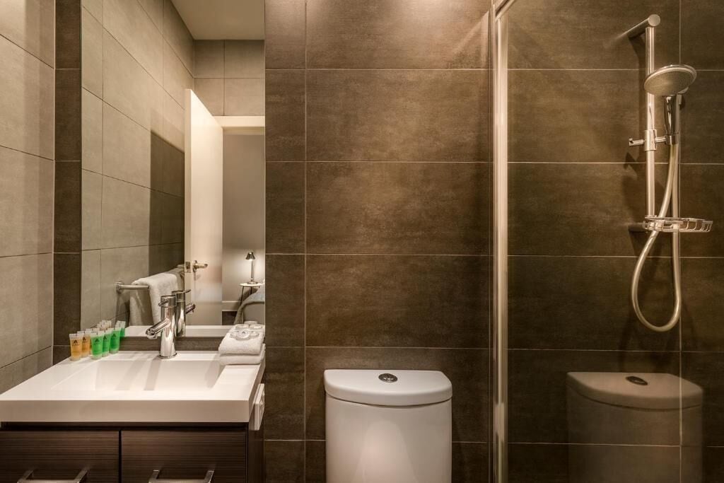A modern bathroom with a shower, toilet, and sink.