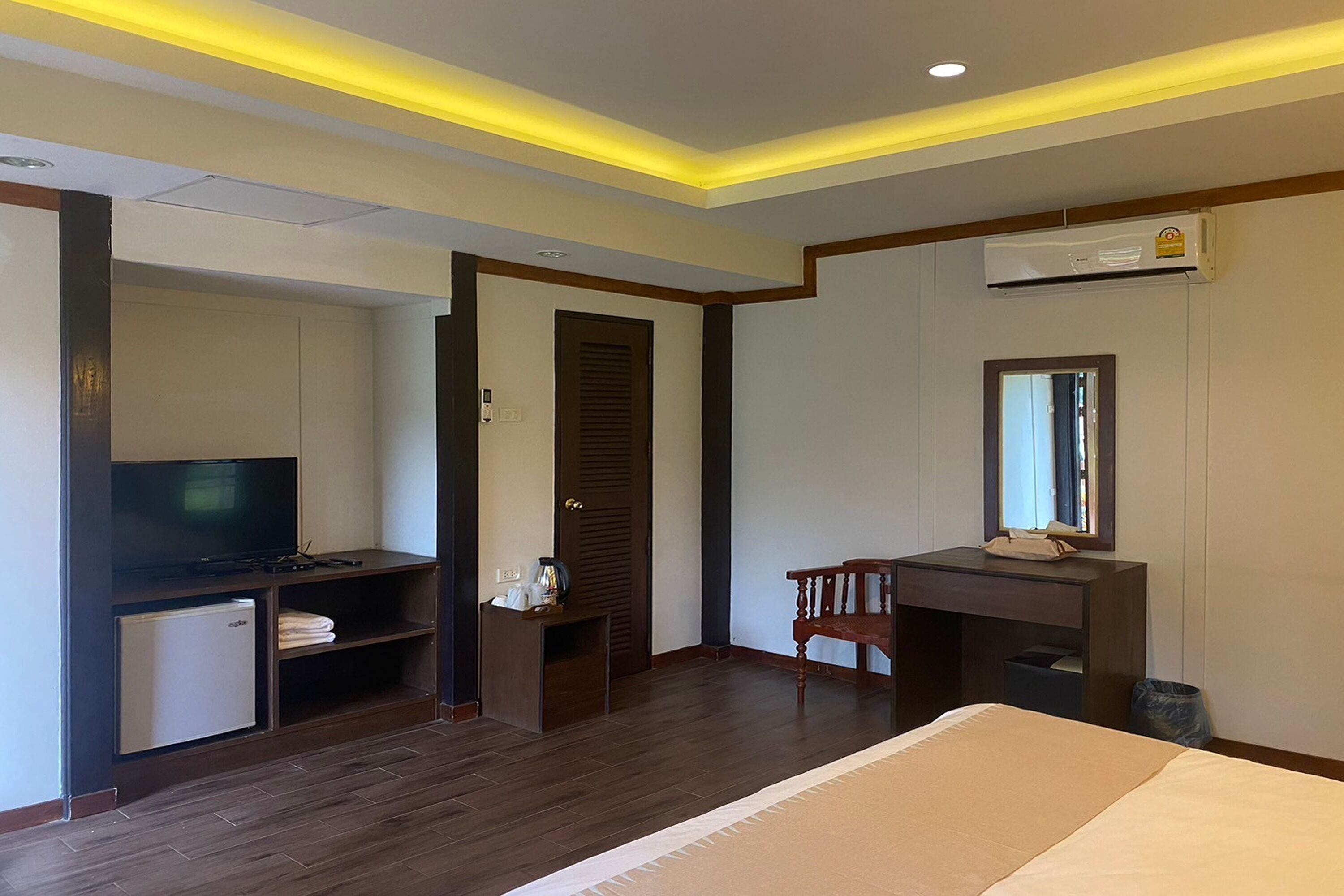 Una habitación de hotel con una cama, un escritorio con silla, televisión y un refrigerador pequeño.