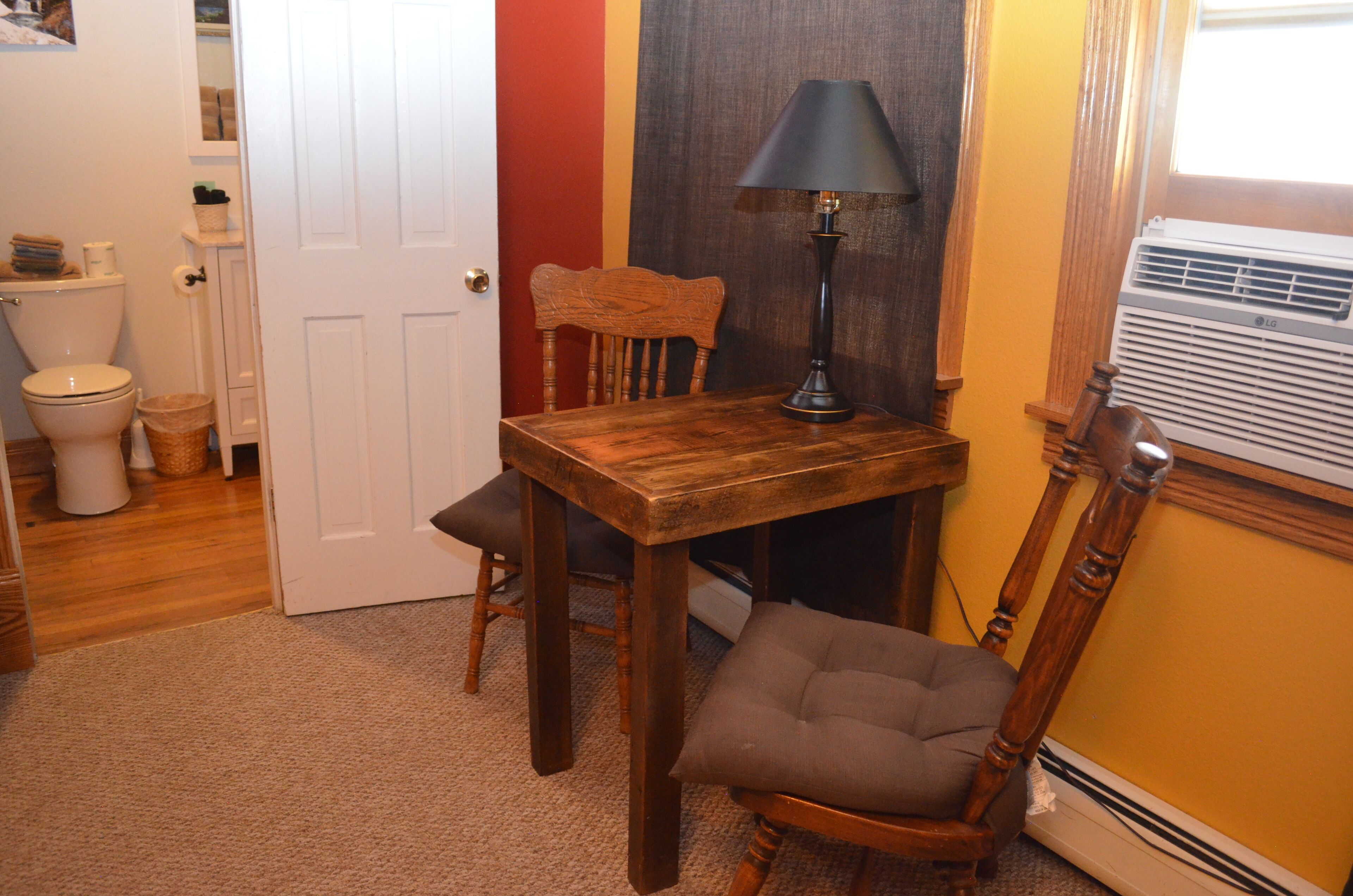 A bathroom with a wooden chair, a table, and a floor lamp.