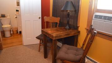 A bathroom with a wooden chair, a table, and a floor lamp.