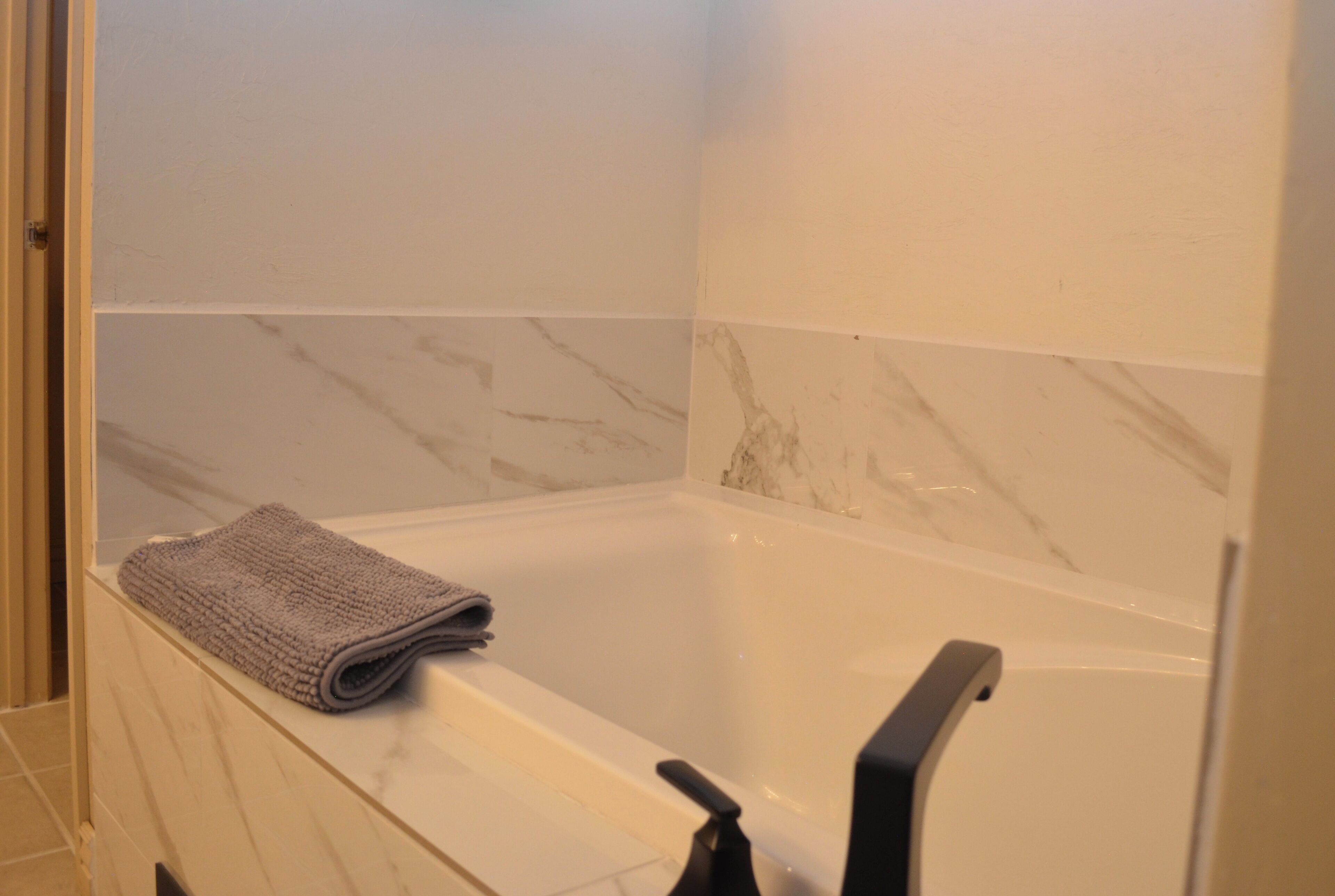 Une salle de bain avec une baignoire, une serviette et des murs en marbre.
