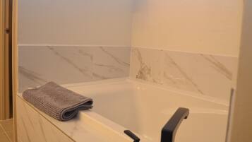 Une salle de bain avec une baignoire, une serviette et des murs en marbre.