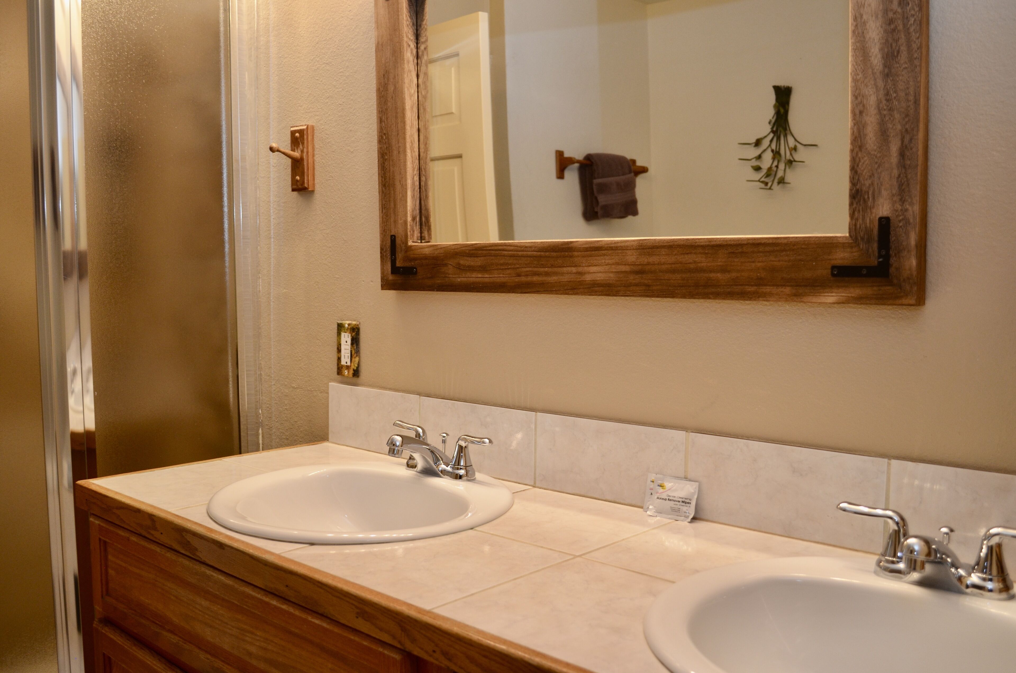 A bathroom with two sinks, a mirror, and a wooden vanity.
