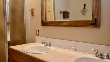 A bathroom with two sinks, a mirror, and a wooden vanity.