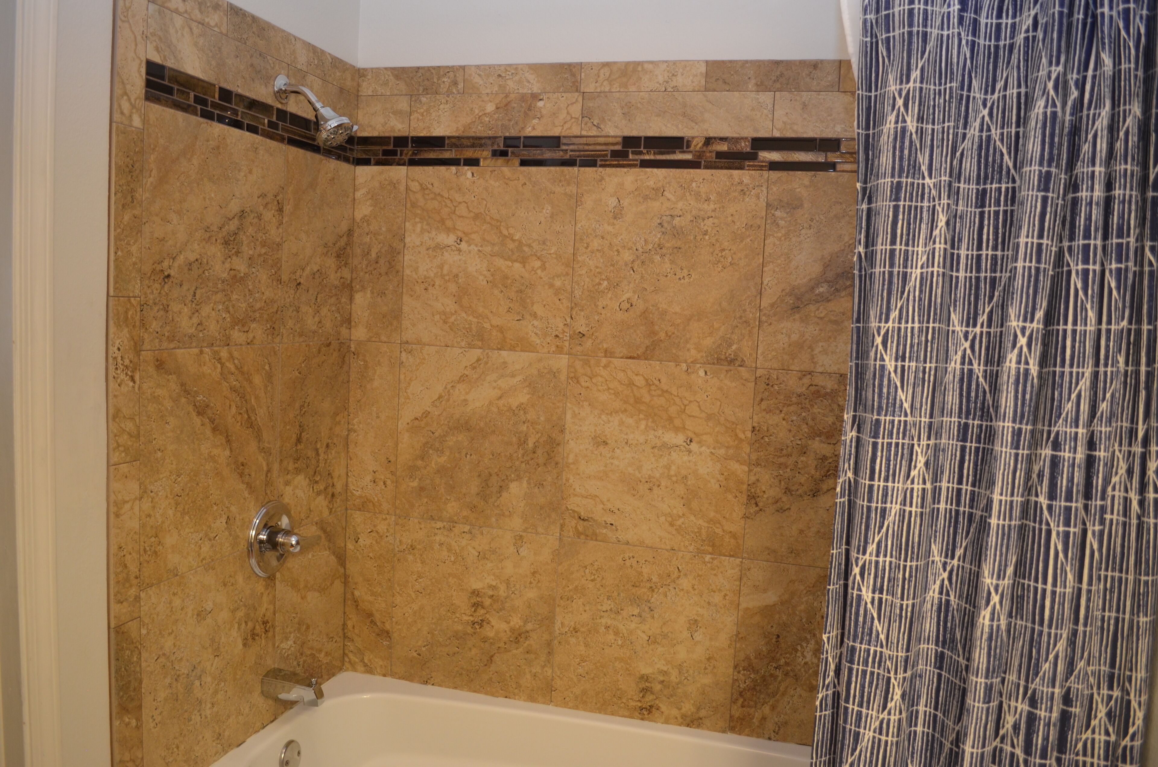 Ein Badezimmer mit Dusche, Badewanne und gefliesten Wänden.