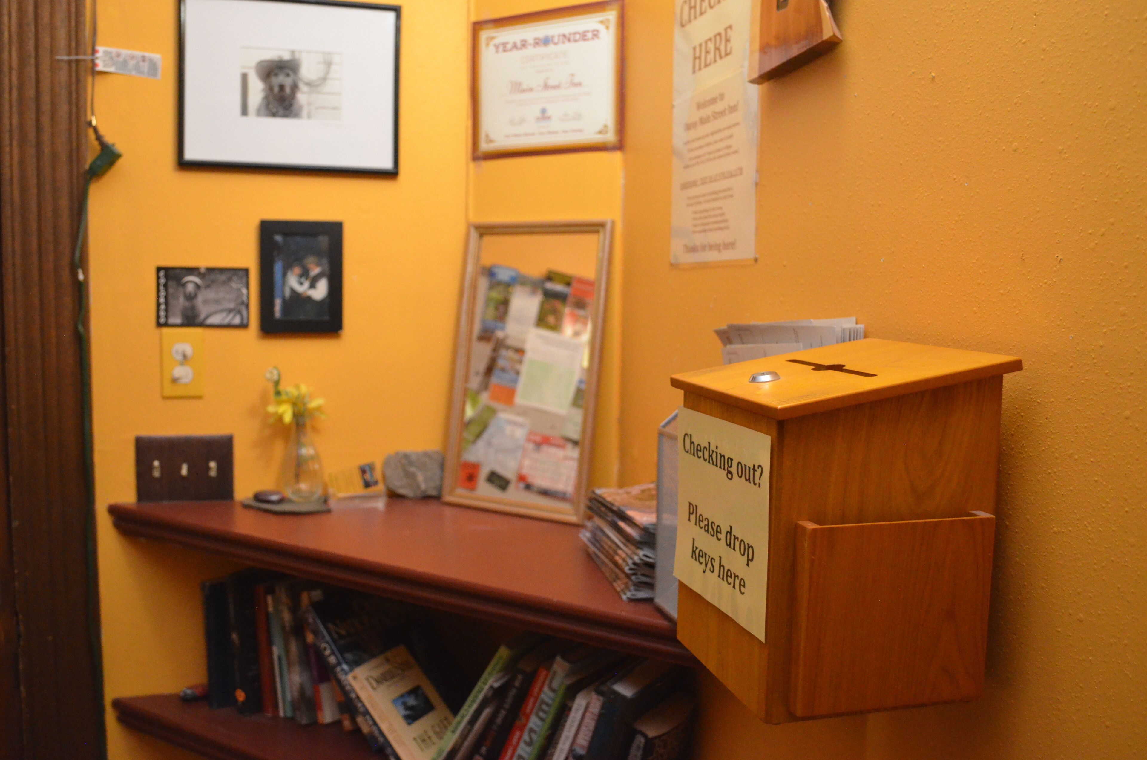 A reception desk with a sign instructing to drop keys, a framed certificate on the wall, and a bulletin board with notices.