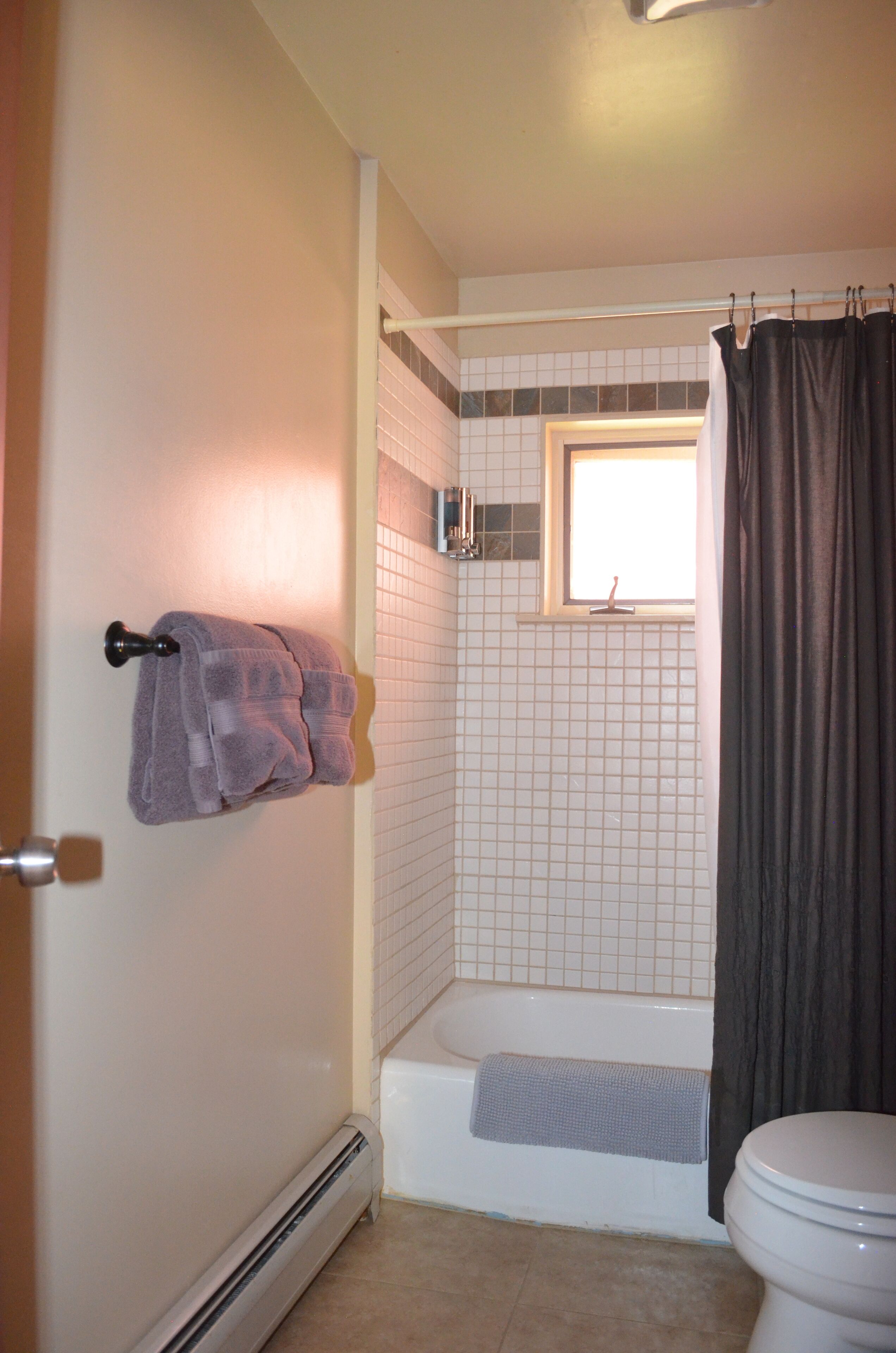 Un baño con una bañera, un inodoro y un perchero con dos toallas.