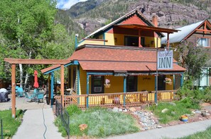 A two-story Main Street Inn with a red roof, yellow walls, and a porch with outdoor seating. - Ouray Main Street Inn (Ouray)