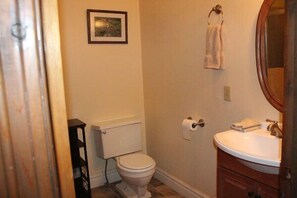 Une salle de bain avec des toilettes, un lavabo et un tableau encadré au mur.