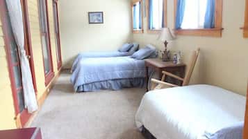 A bedroom with two beds, a desk, and a chair.