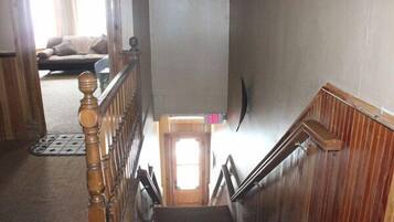 Una escalera de madera con barandilla que lleva a una puerta señalizada con “EXIT”.