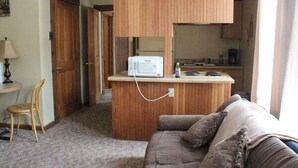 A compact living space with a kitchenette, a sofa, and a chair. - Smedley's Suites (Silverton)