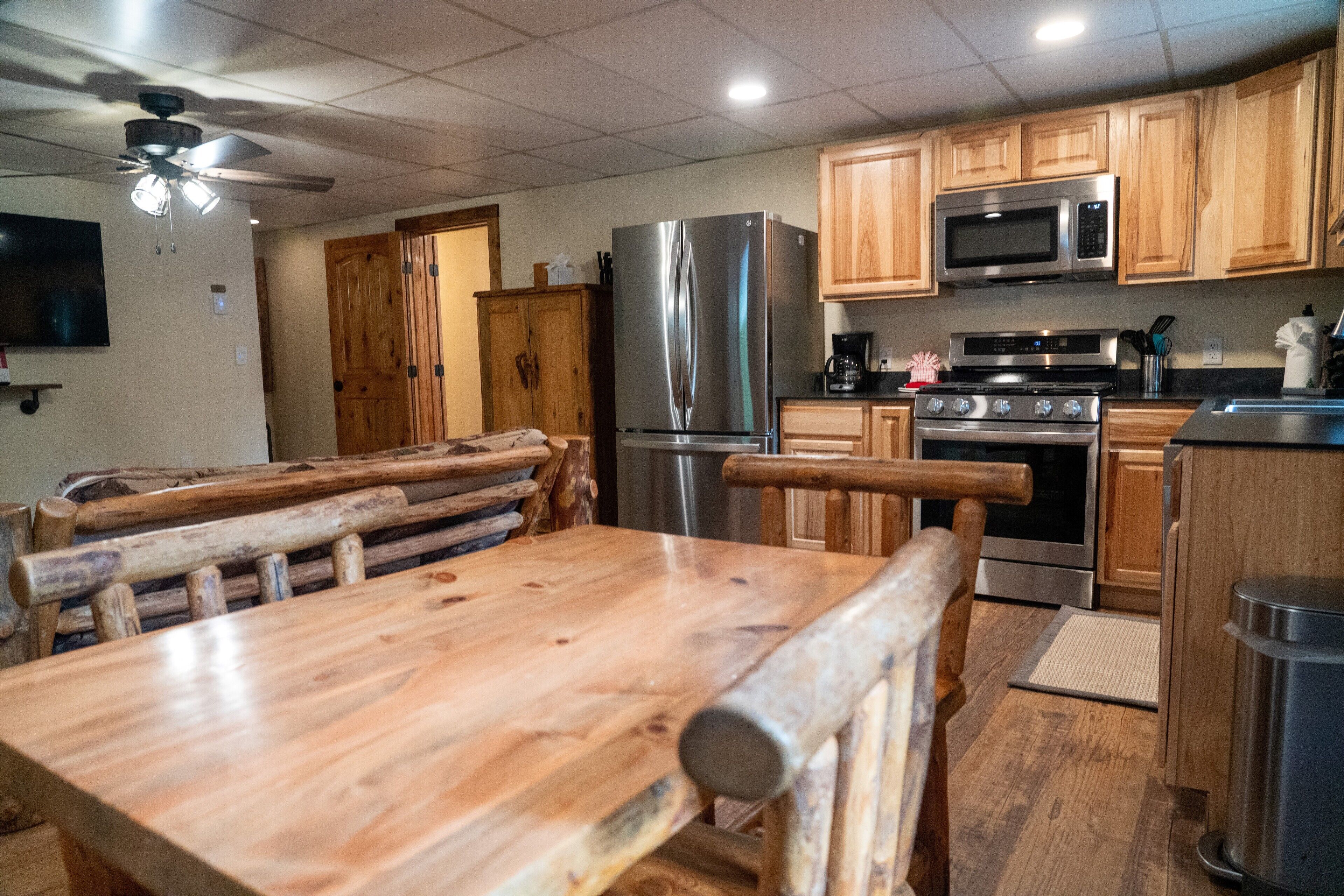 A kitchen with wooden cabinets, stainless steel appliances, and a wooden dining table.