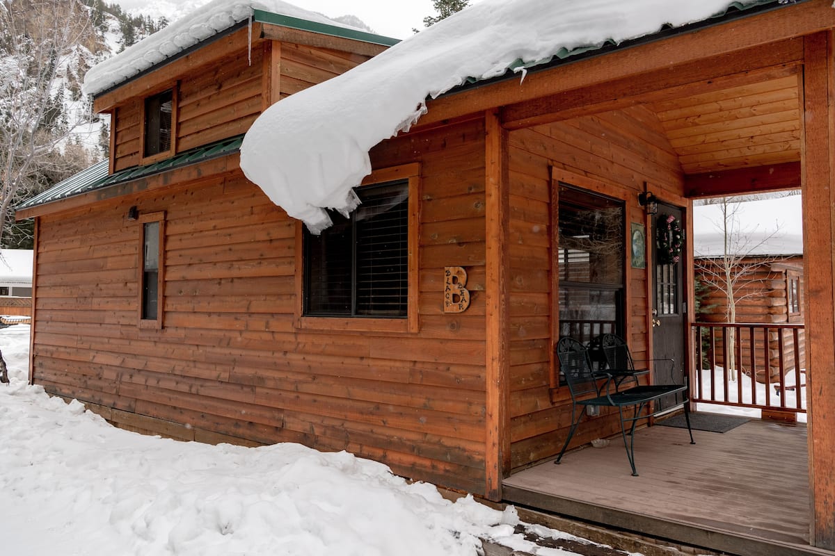 A wooden cabin with a porch, a window, and a door.