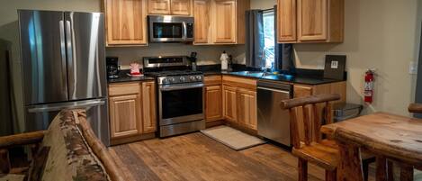 A compact kitchen with wooden cabinets, stainless steel appliances, and a wooden dining area.