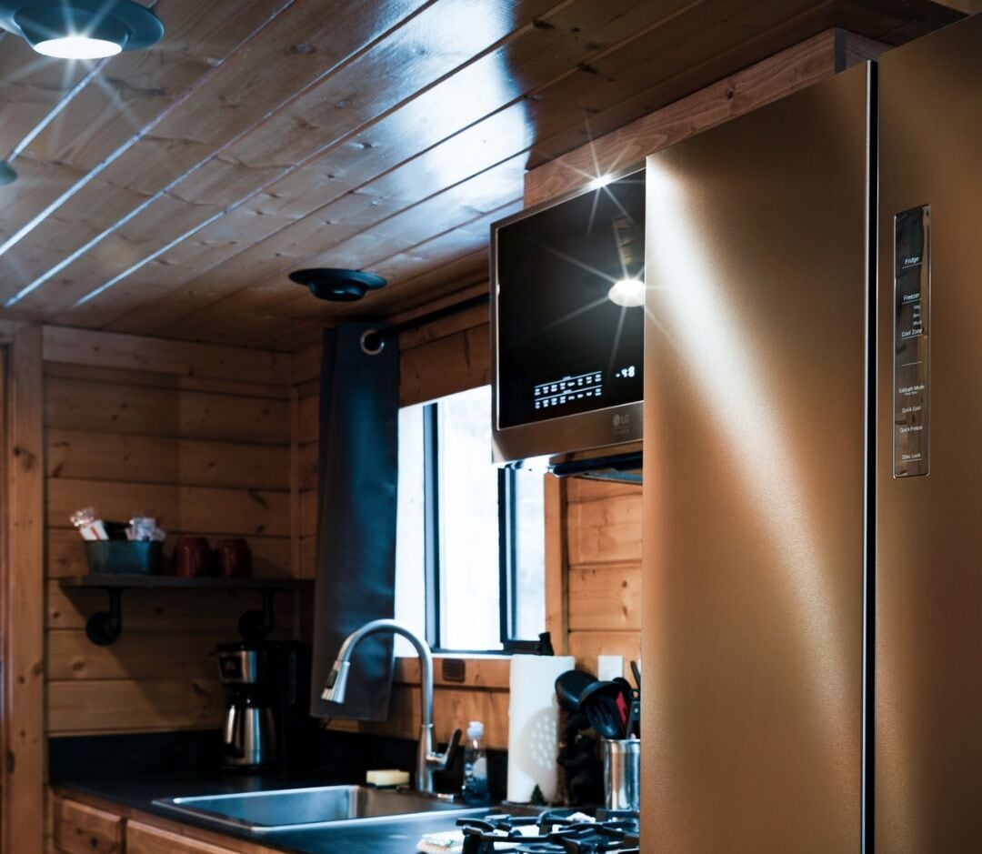 Une cuisine moderne avec des murs en bois, un réfrigérateur en acier inoxydable et un four encastré.