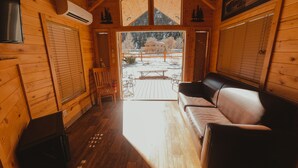 A wooden cabin interior with a sofa, a chair, and a table outside. - Ouray Riverside Resort - Inn & Cabins (Ouray)