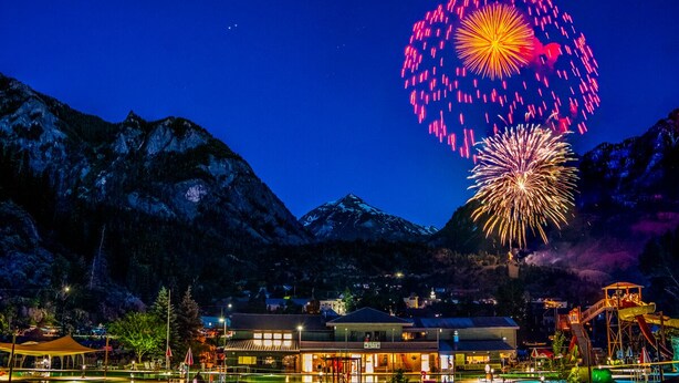 A hotel with a pool, outdoor seating, and a view of mountains. - Ouray Riverside Resort - Inn & Cabins (Ouray)