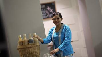 A person arranging bottles and glasses on a table with a basket.