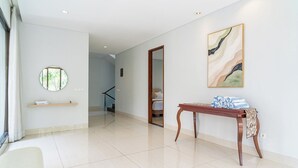 A spacious hallway with a round mirror, a wooden table with a patterned cloth, and a painting on the wall. - Hikari Hill View 7BR Villa with a Private Pool (Cimenyan)