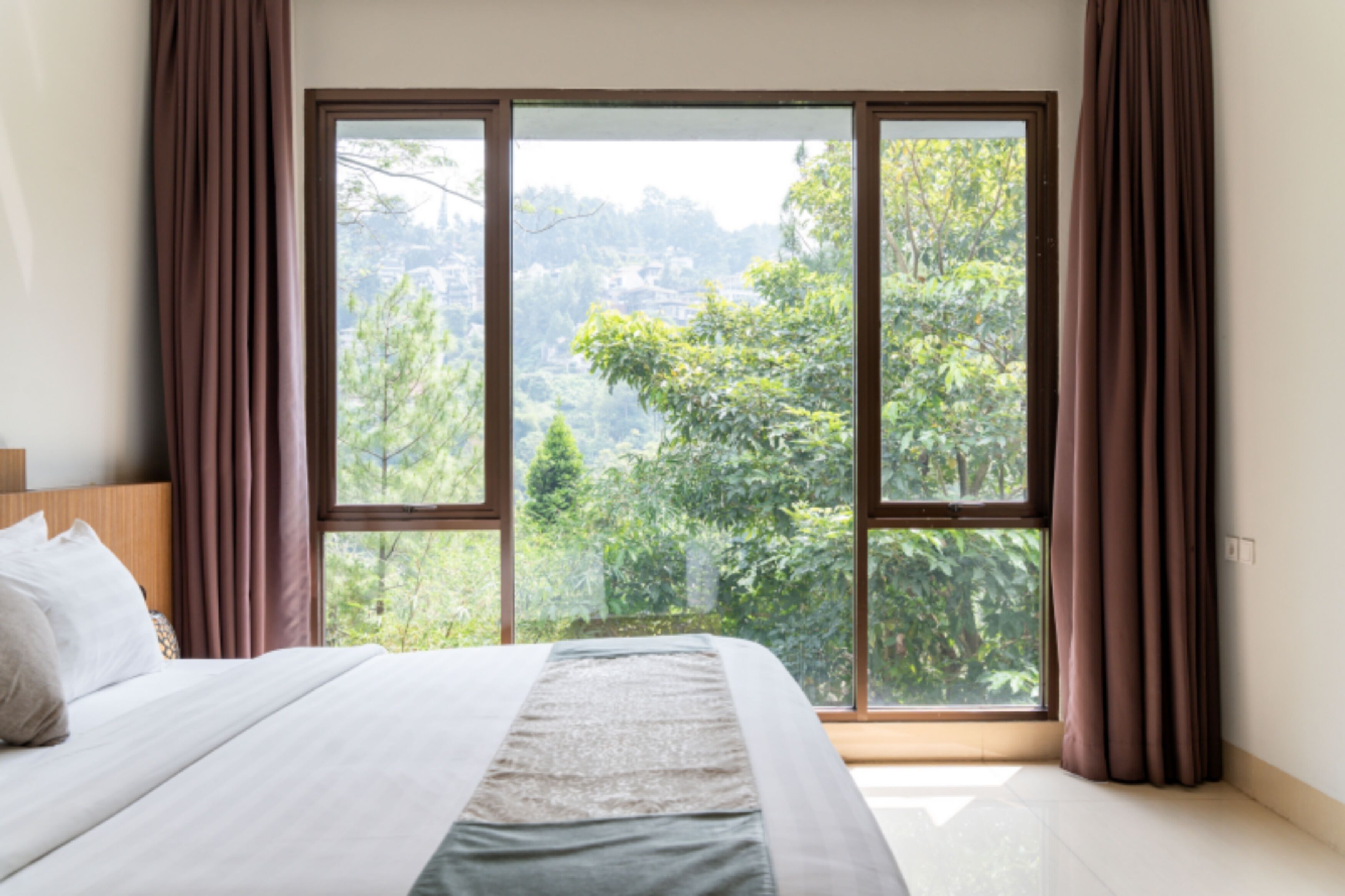 Un dormitorio con una ventana grande, una cama y cortinas.