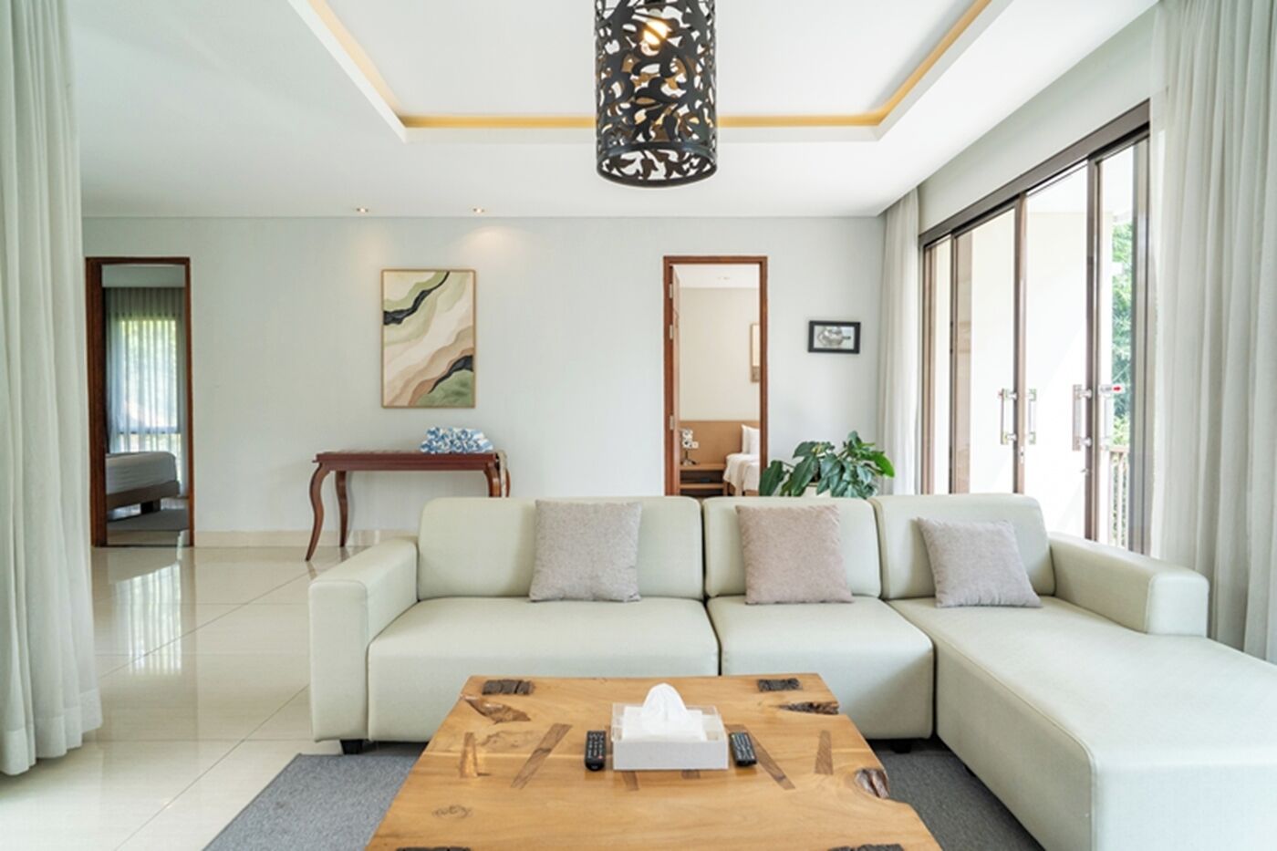 A modern living room with a sectional sofa, a wooden coffee table, and a large window.