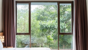 Un dormitorio con un ventanal, una cama y cortinas.