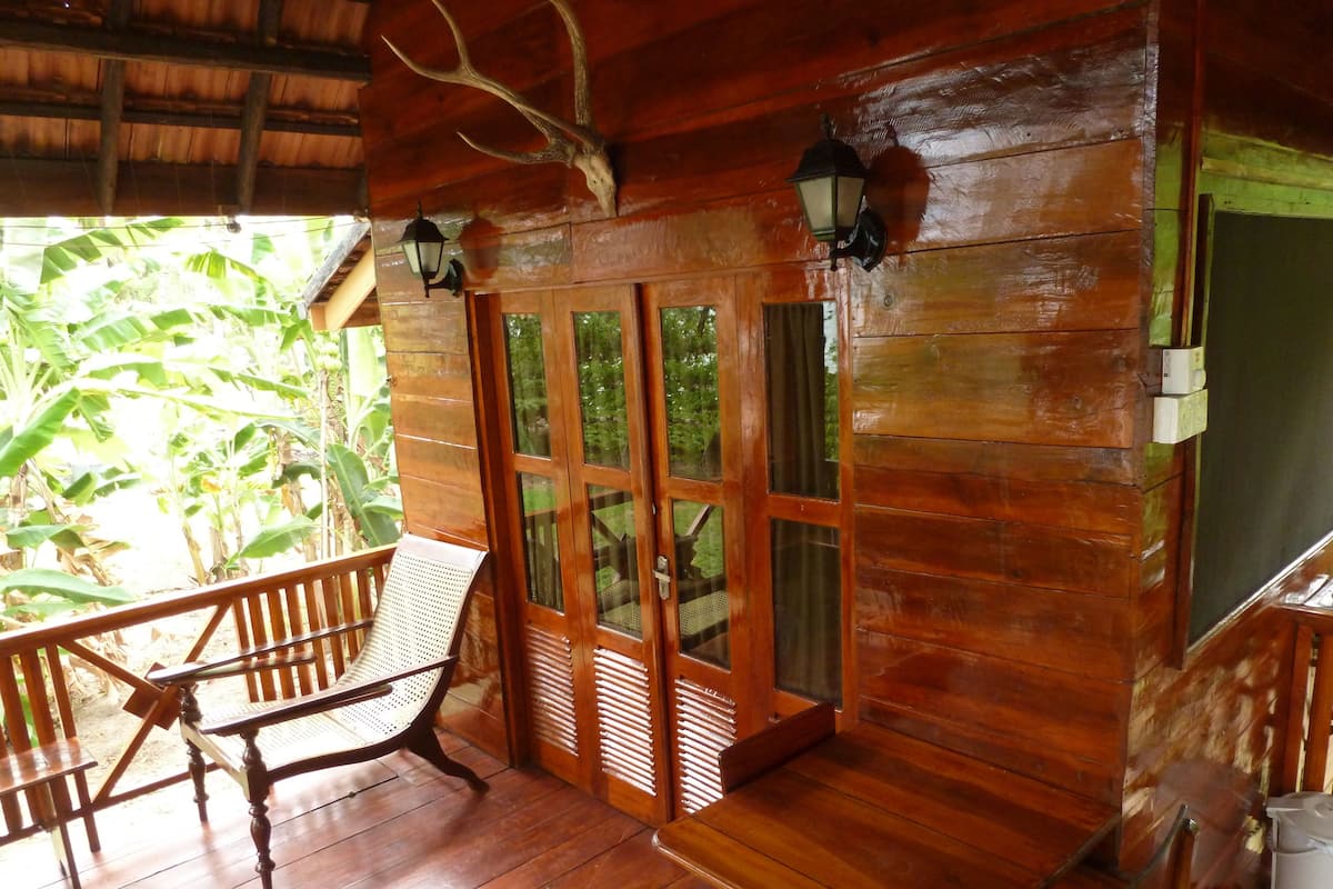 A wooden cabin with a porch, a bench, and a table.