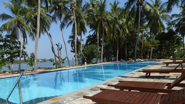 A swimming pool with lounge chairs and palm trees. - Riviera Resort (Manmunai North)