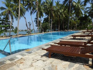A swimming pool with lounge chairs and palm trees.