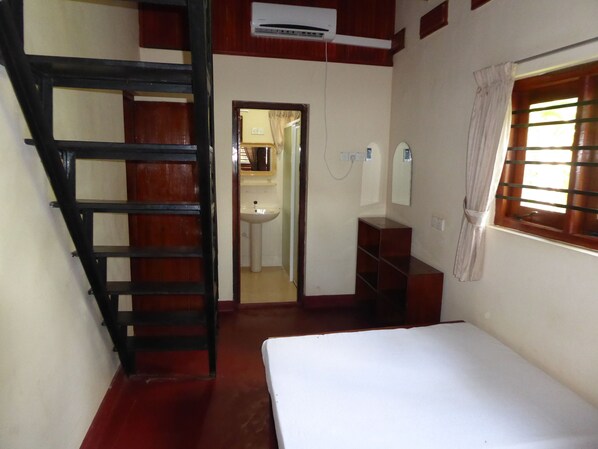Un dormitorio con una cama, una escalera de madera, un lavabo y una ventana con barrotes.