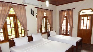 A hotel room with two beds, wooden floors, and large windows with curtains. - Riviera Resort (Manmunai North)