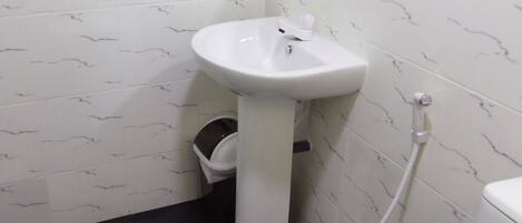 A bathroom with a white sink, toilet, and a shower area.