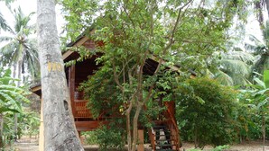 A wooden structure with a porch and a staircase leading to a platform, surrounded by dense foliage and trees. - Riviera Resort (Manmunai North)