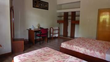A bedroom with two beds, a desk with a chair, a hanging painting, and a wooden ceiling.