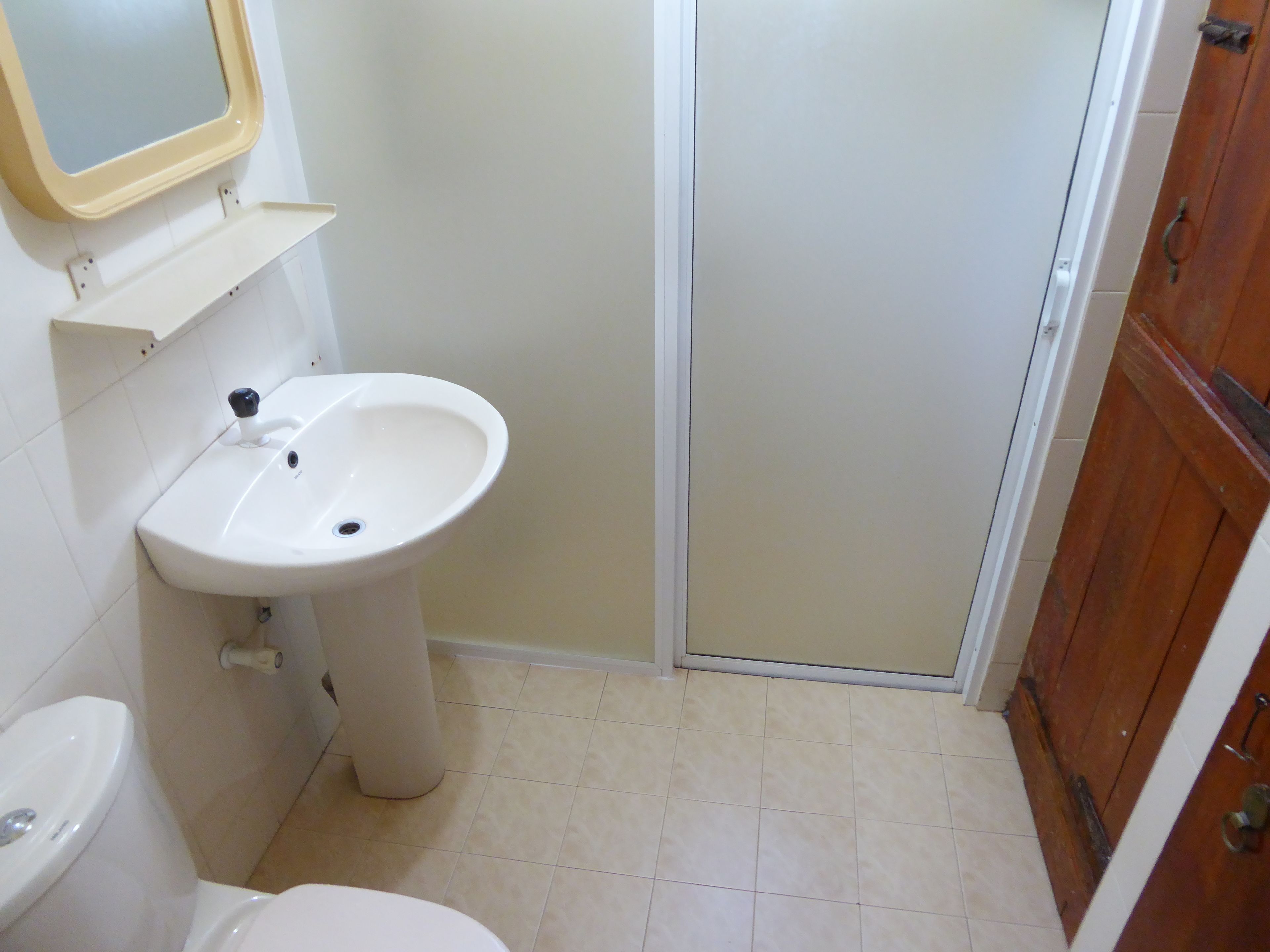 Une salle de bain avec un lavabo blanc, des toilettes et une porte en bois.