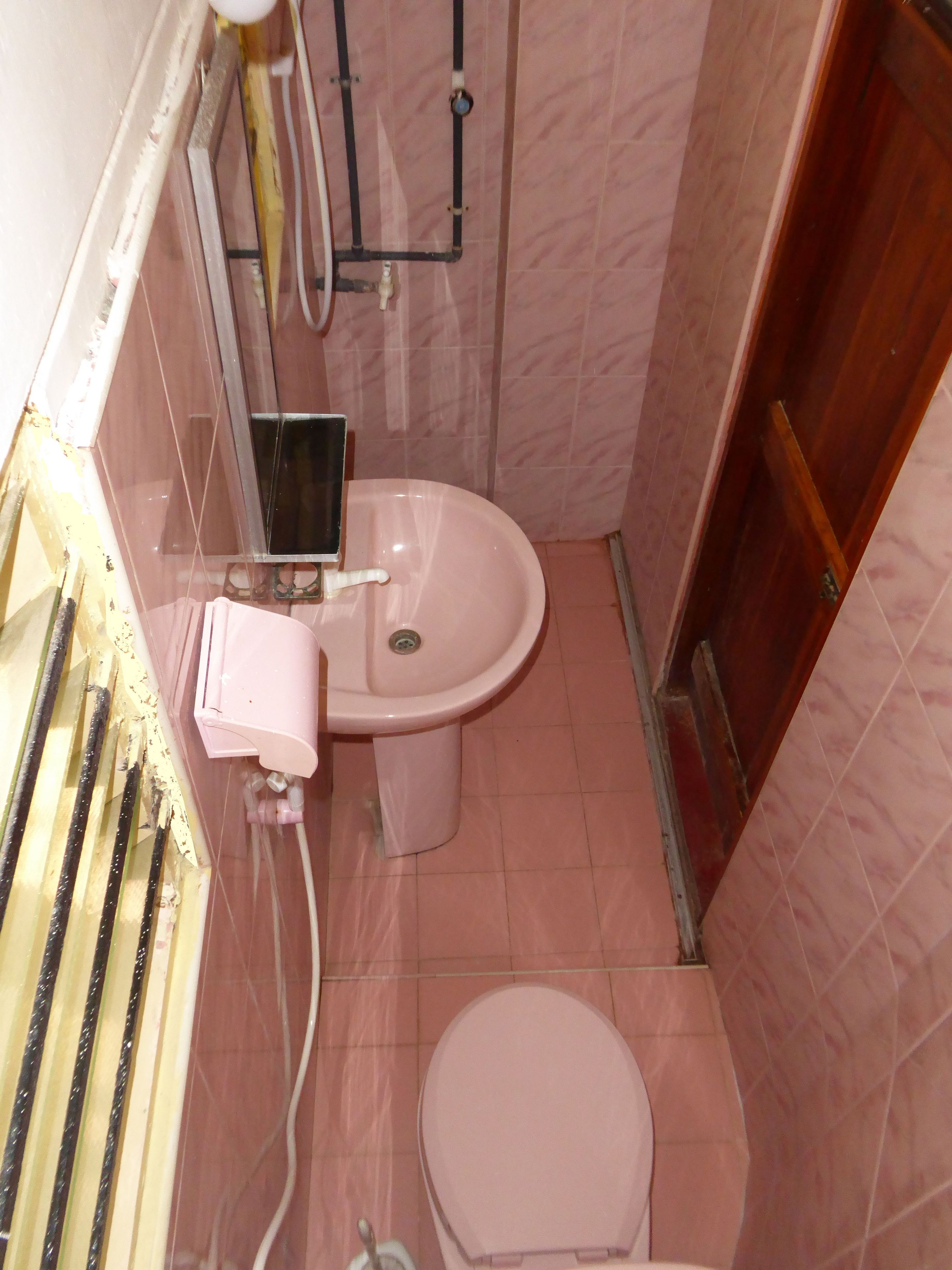A small bathroom with a toilet, sink, and shower area.