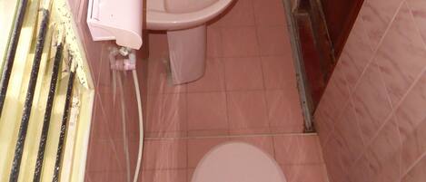 Une petite salle de bain comprenant des toilettes, un lavabo et un espace douche.