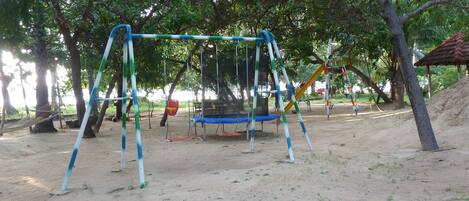 A playground with swings, a trampoline, and a slide.